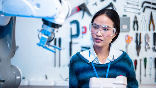 Student engineer studying a robotic arm. Student engineer studying a robotic arm.